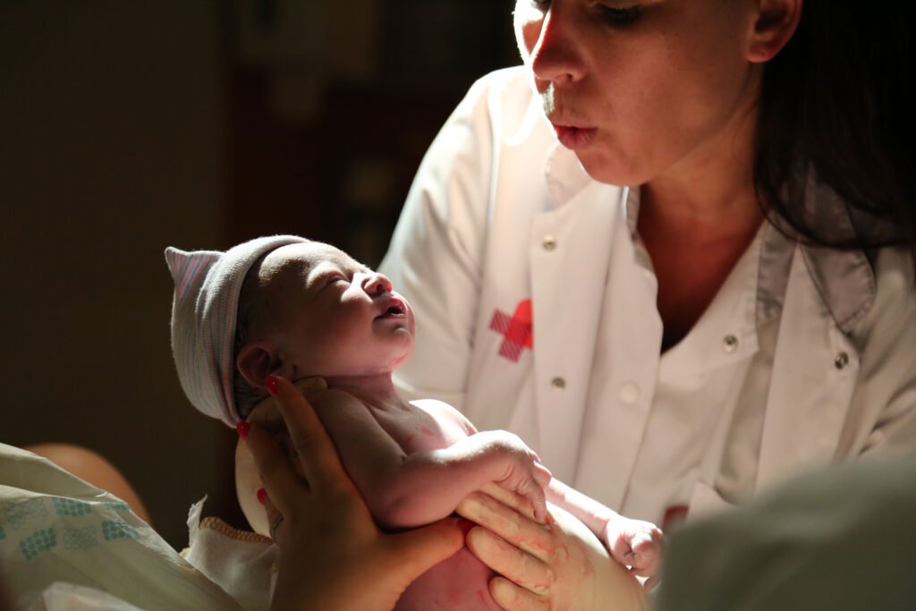Newborn baby being lifted gently right after birth in hospital in The Hague.