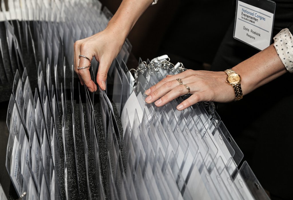 Hands organising event badges during registration at a business conference in The Hague.