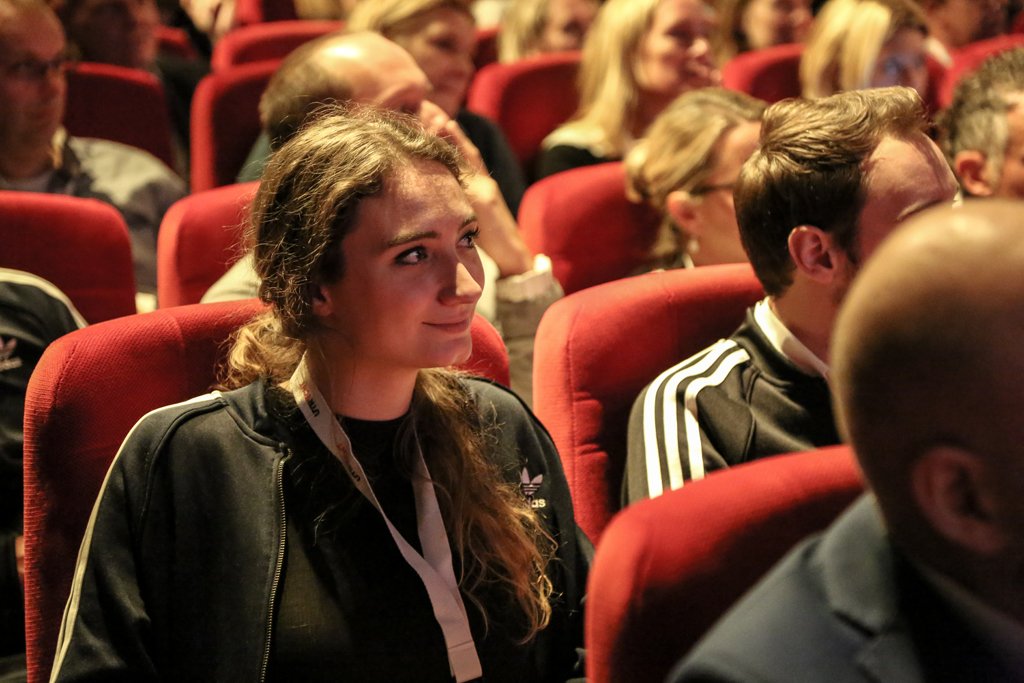 Young woman listening attentively in a conference audience in The Hague.