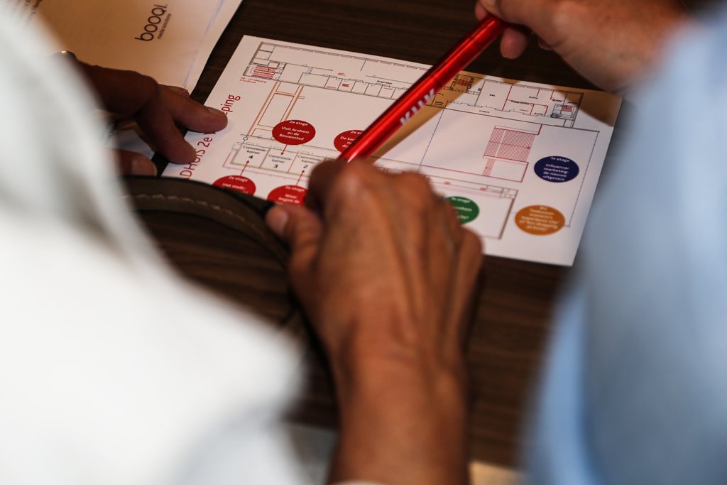Close-up of hands reviewing an event floor plan during a business conference workshop in The Hague.