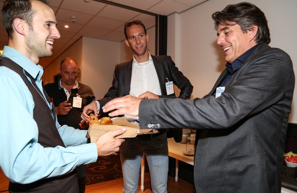 Attendees receiving pastries during a networking break at a corporate event in The Hague.