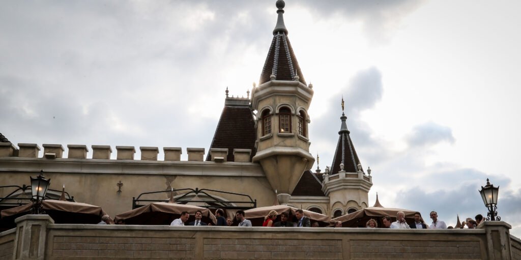 Guests socializing on a terrace with castle-like architecture during an outdoor event in The Hague.