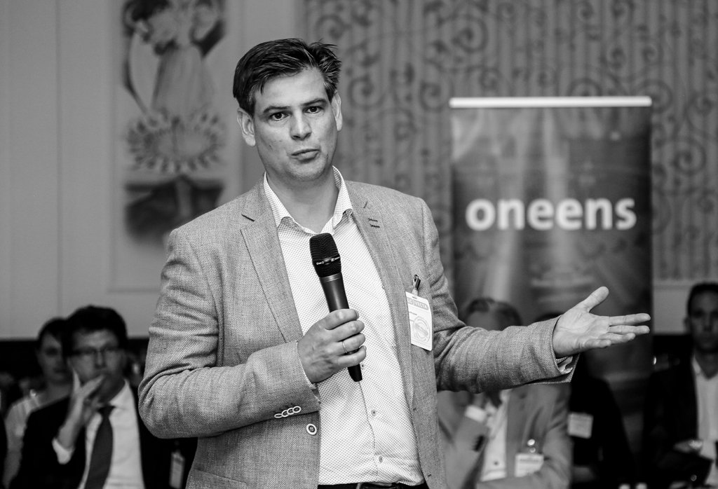 Corporate speaker holding a microphone while presenting to an audience in The Hague.