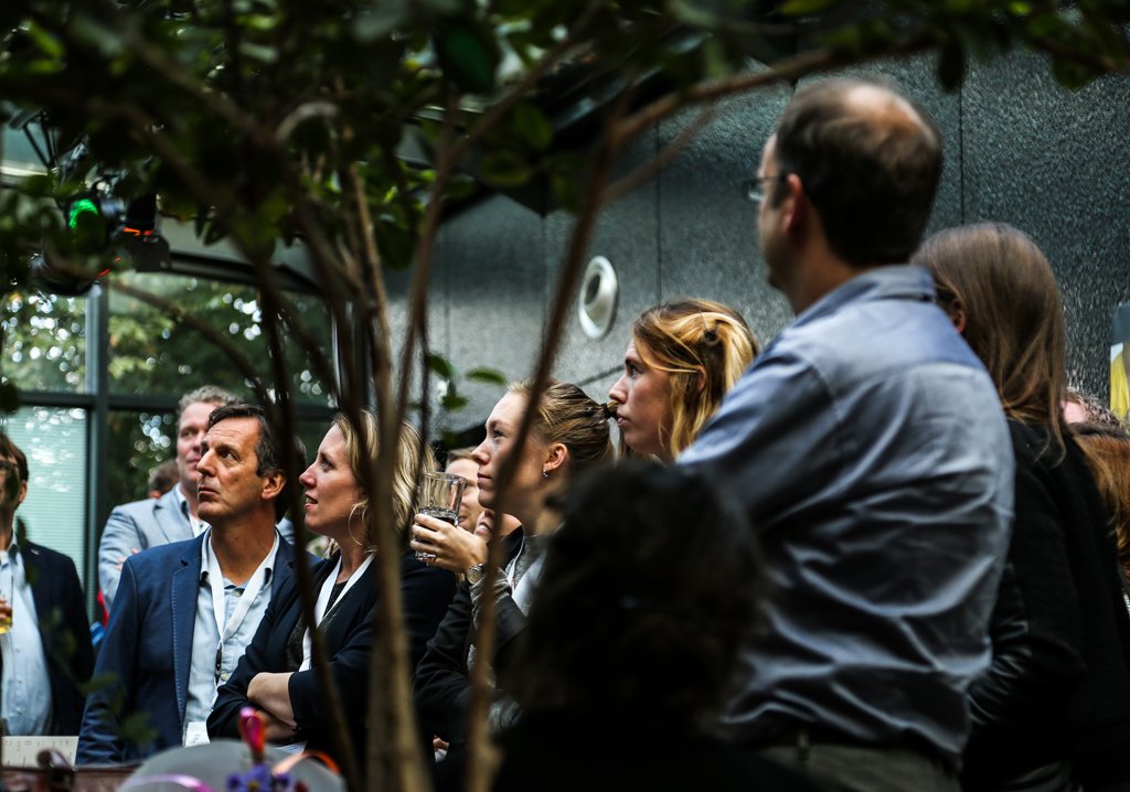 A group of attendees watching a presentation in an indoor garden venue in The Hague.