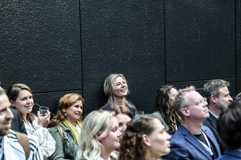 Audience members smiling and engaged during a presentation at a corporate event in The Hague.