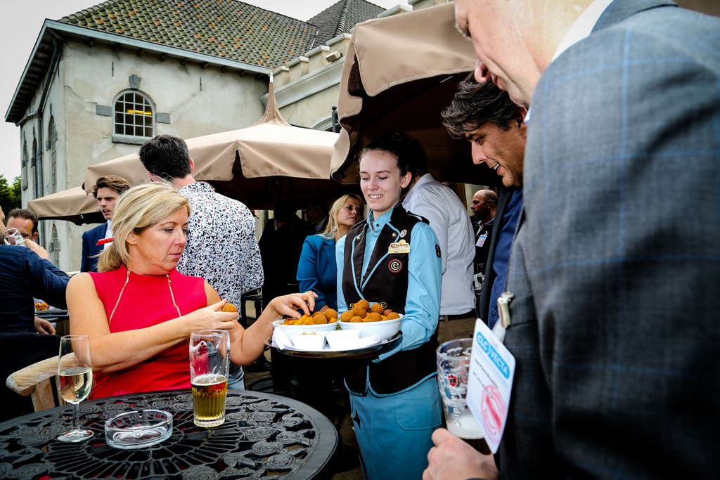 Guests enjoying drinks and bitterballen served by staff during a business event in The Hague.