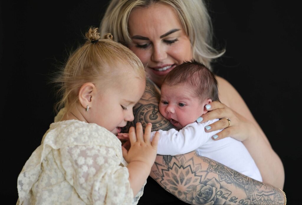 Mother with her toddler and newborn baby during a connected and emotional studio moment.