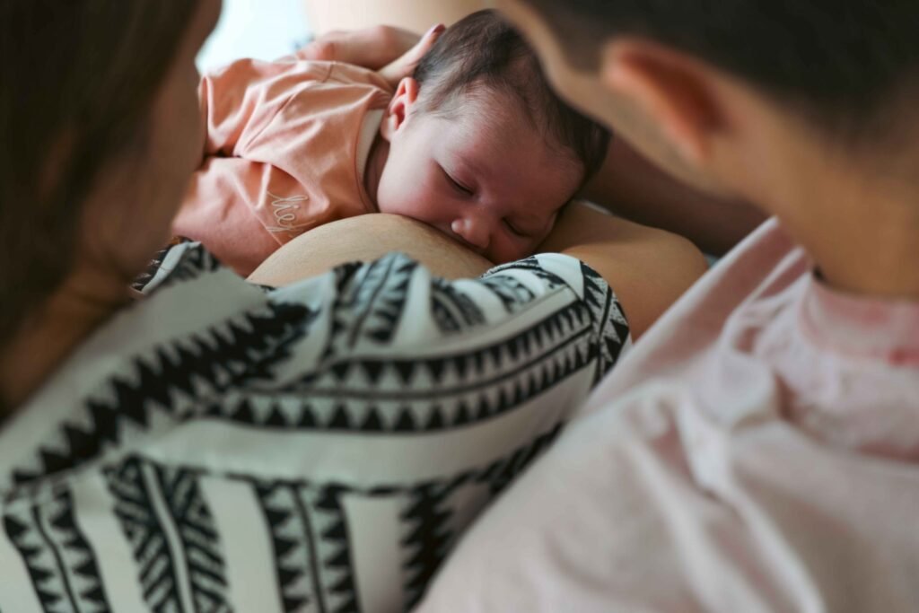 Newborn breastfeeding while both parents sit closely during an intimate lifestyle session