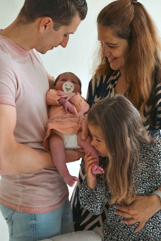 Family gathered closely around their newborn baby during a warm home photography session