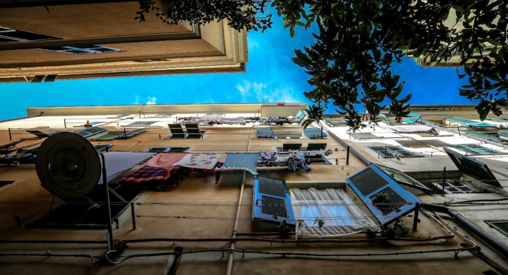Upward view between narrow urban buildings with laundry lines and blue sky