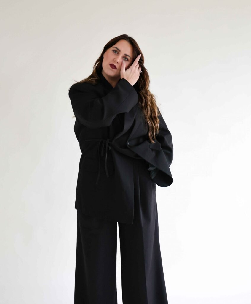 Editorial-style professional portrait of a woman in a black outfit against a light background – The Hague.