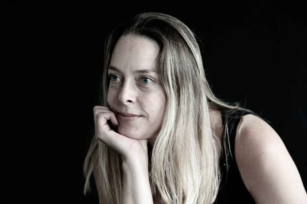 Soft-lit studio portrait of a woman with natural expression against a dark background – The Hague.