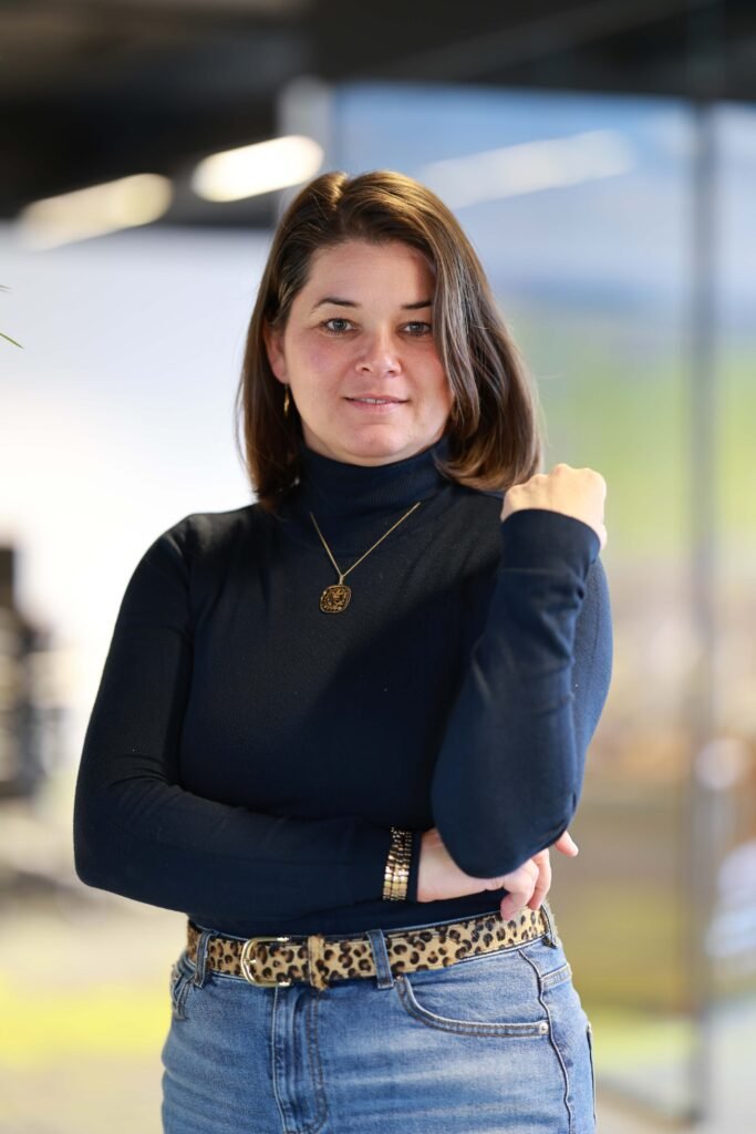 Professional LinkedIn portrait of a woman posing confidently in a modern office environment in The Hague.