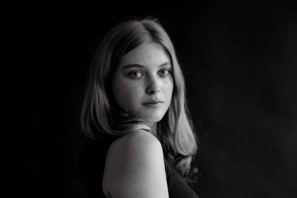 Professional black-and-white studio portrait of a young woman looking confidently into the camera – The Hague.