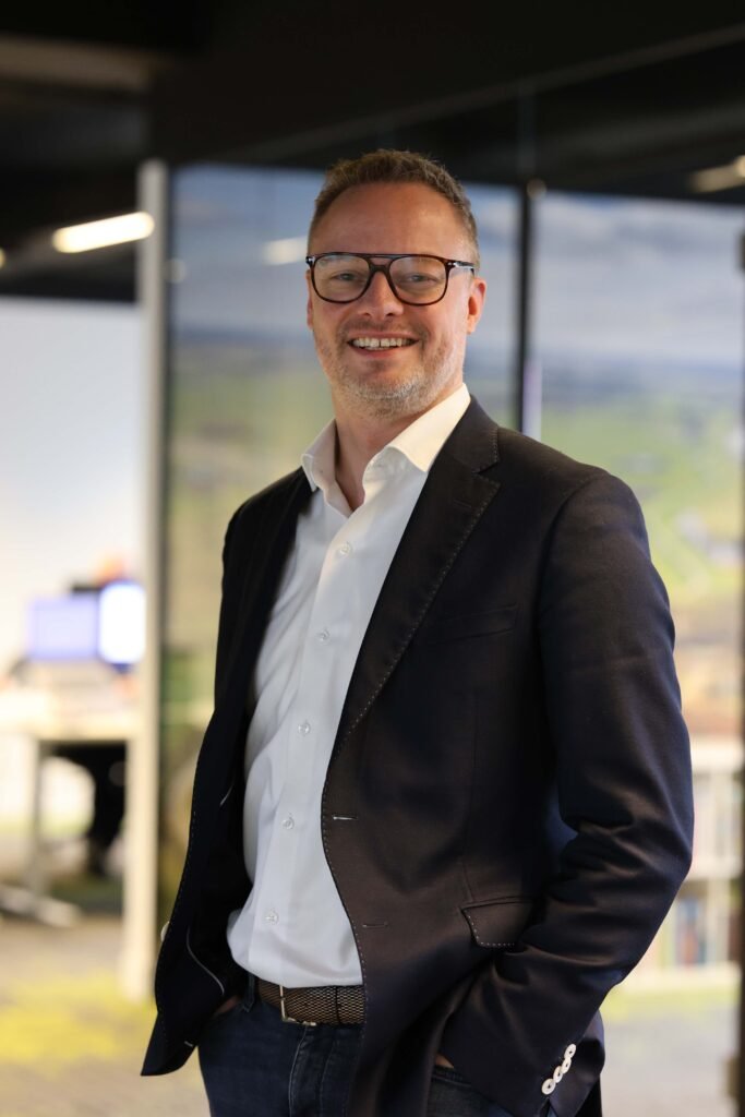 Professional man smiling in a modern office setting — LinkedIn business portrait photographed in The Hague.