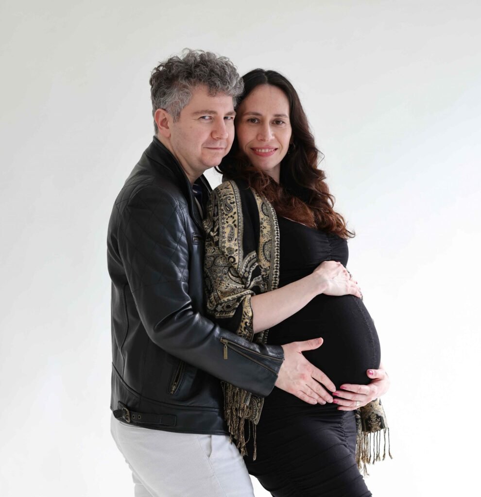 Expecting couple posing together with hands on the pregnant belly during a studio maternity session in The Hague.