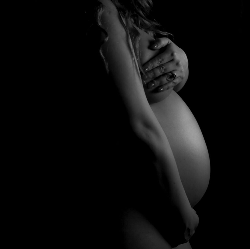 Low-key black and white fine art maternity photo focusing on the pregnant belly, The Hague.