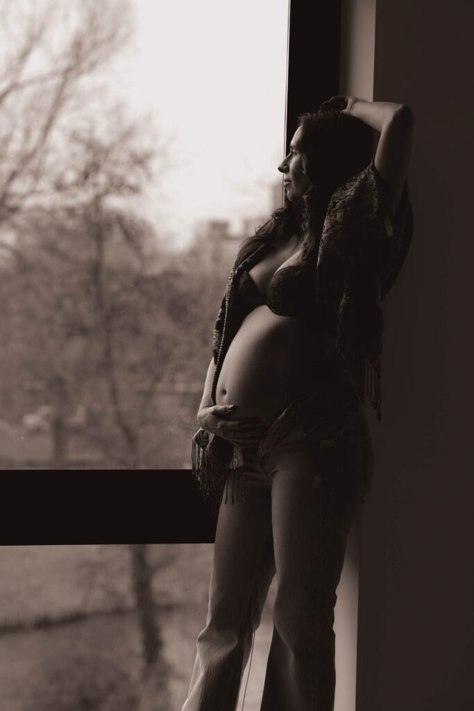 Maternity portrait in soft window light with expecting mother posing thoughtfully in The Hague.