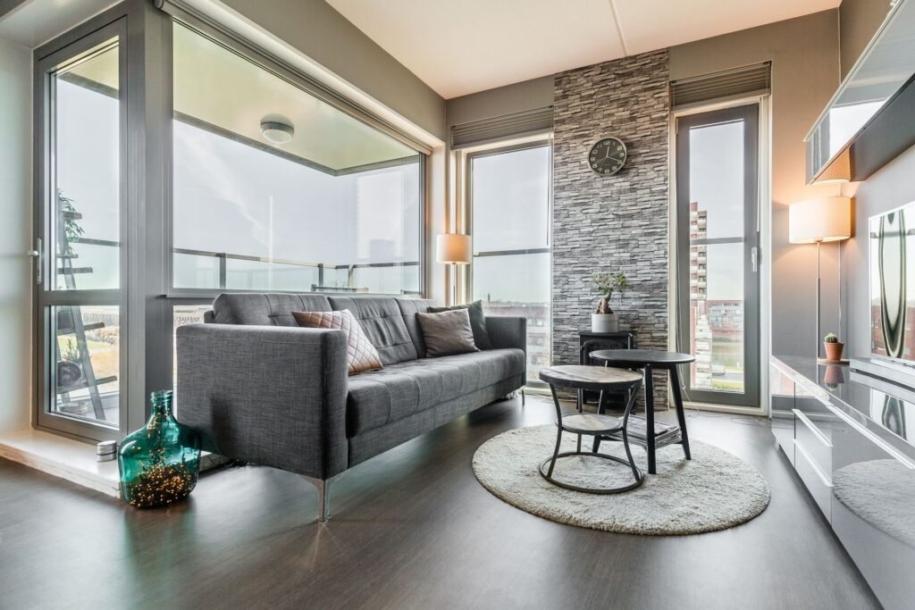 Modern apartment living room with panoramic windows and grey sofa in The Hague