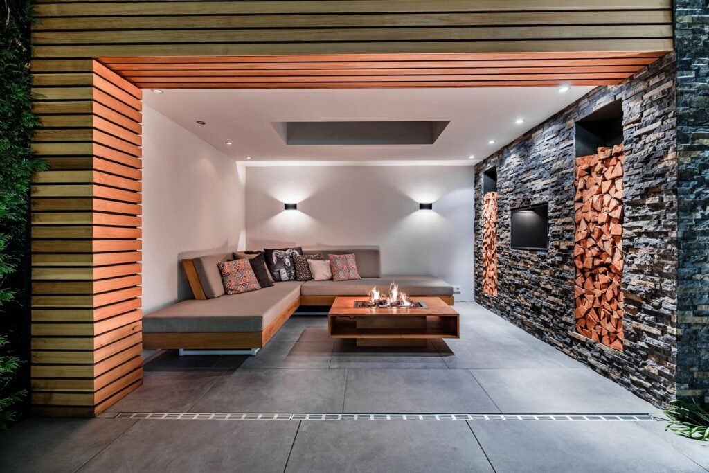 Covered outdoor lounge with firepit, stone wall and wood details in modern The Hague residence