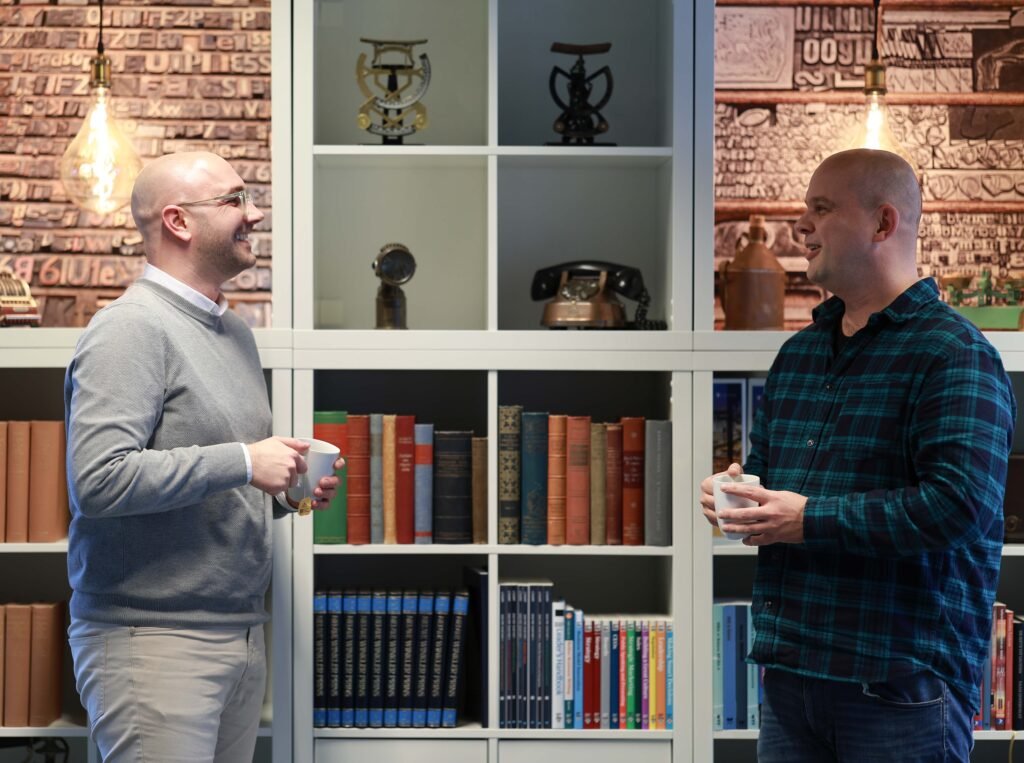 Two colleagues talking and smiling in an office library space in The Hague